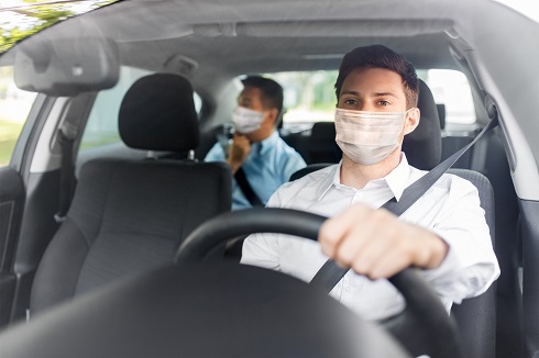 taxi driver in face protective mask driving car alternate text for this image