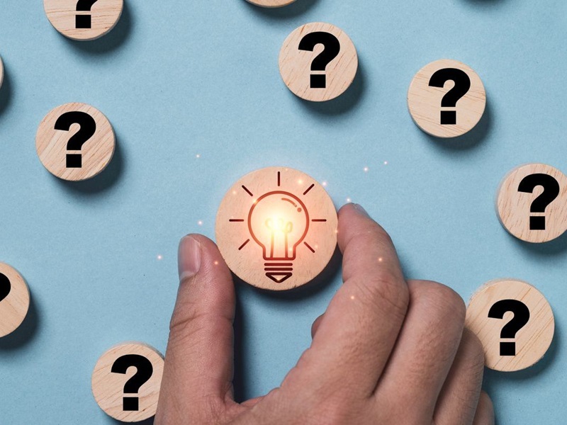 Hand holding glowing light bulb inside magnifier glass