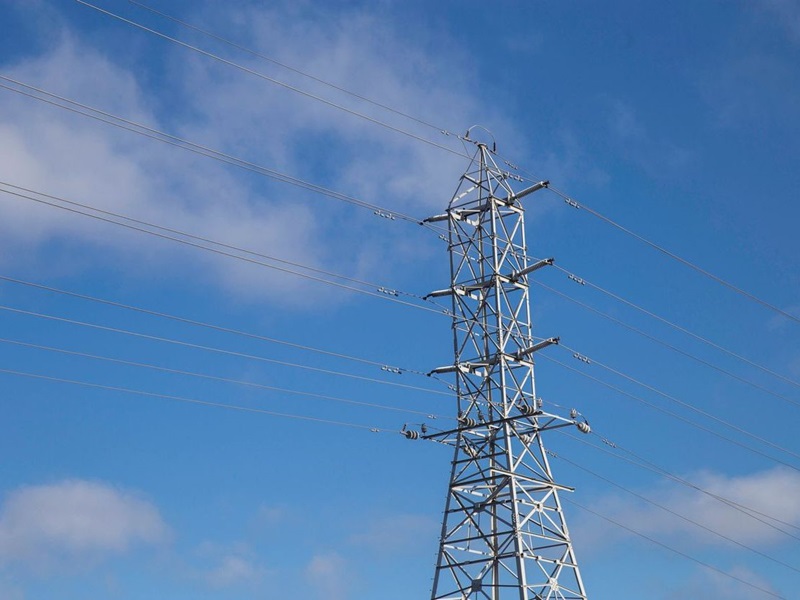 Transmission tower against a blue cloudy sky