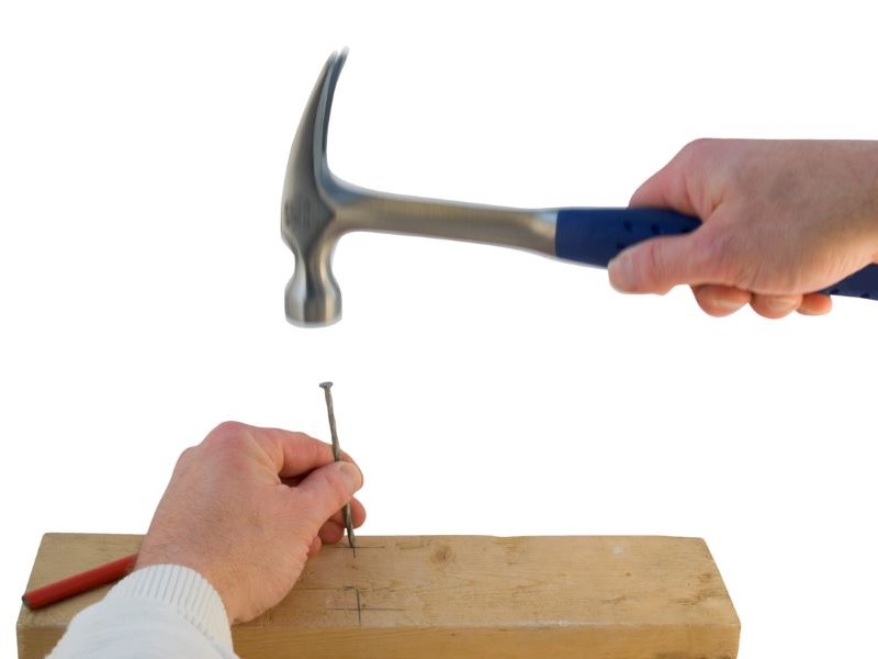Hammer about to hit someone's hand.