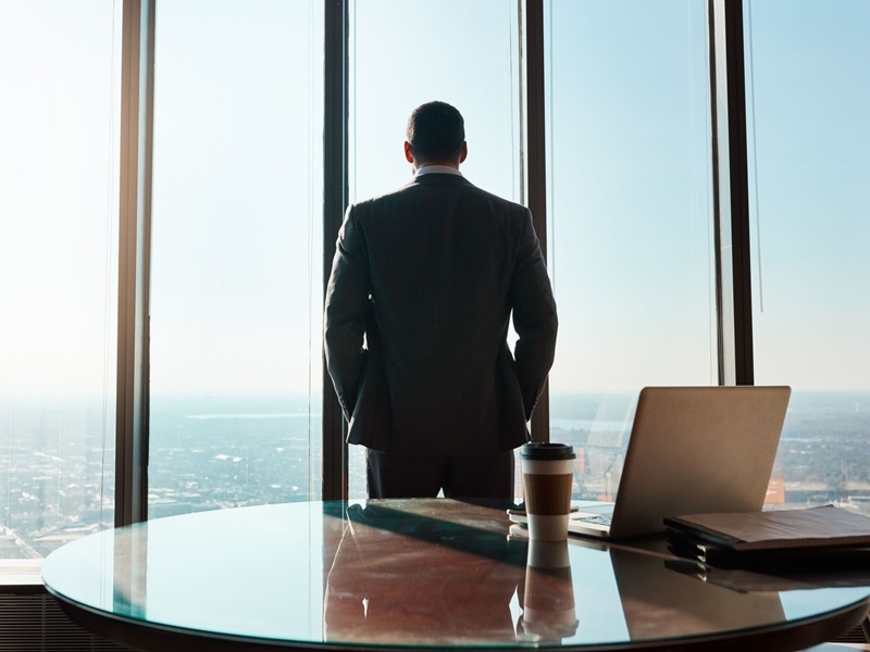 Rearview shot of a young businessman looking out the window in an office