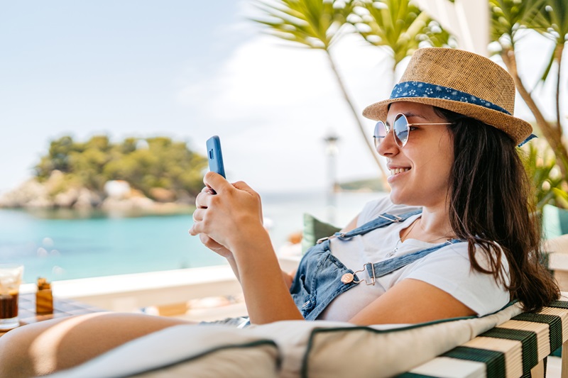 Young Woman Using Her Phone At A Seaside Café