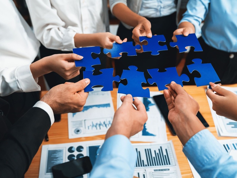 Business people holding jigsaw pieces and merging them together