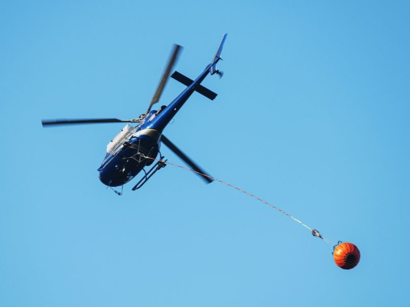 Helicopter carrying water bucket to a fire