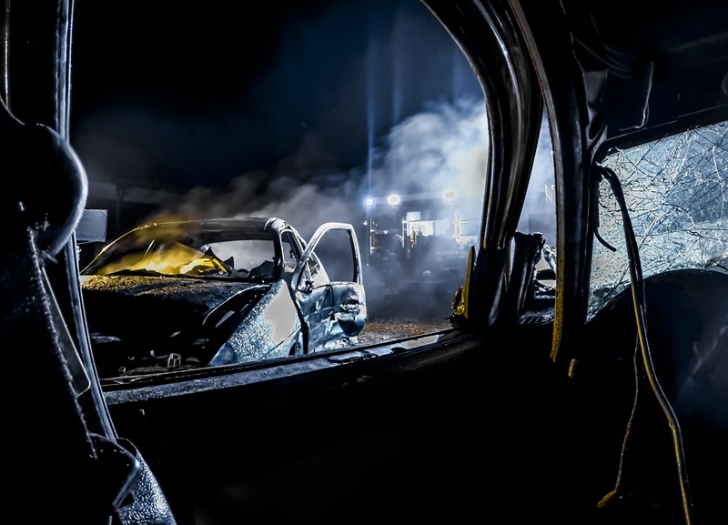 Crashed car burning at night.