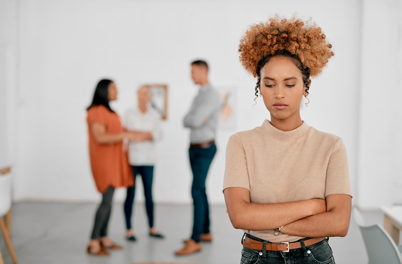 Shot of a young businesswoman being excluded from her colleagues in a modern office
