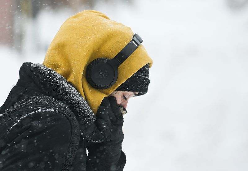 A person covers up during a snowstorm in Montreal, Sunday, Feb. 16, 2025. THE CANADIAN PRESS/Graham Hughes