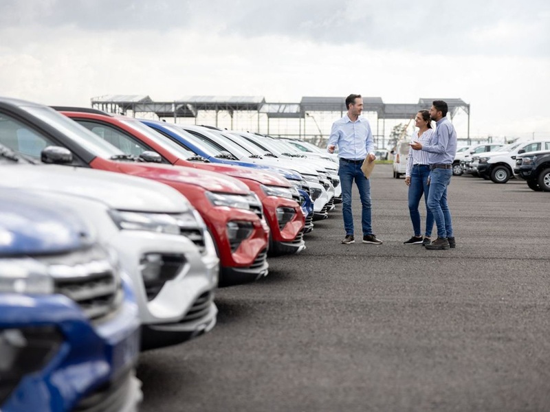 Salesman showing cars to a couple at the dealership