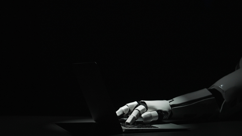 Robot Hand Typing on Laptop in Dark Environment with Dramatic Lighting alternate text for this image