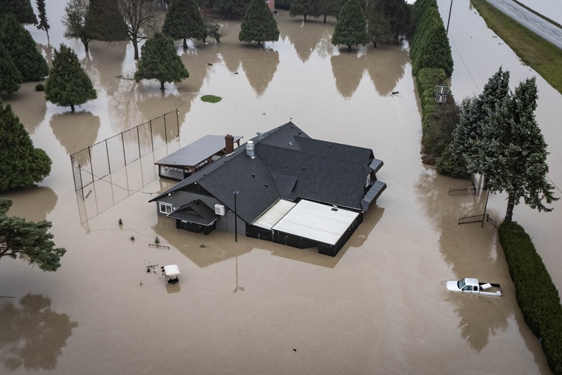 Floodwaters surrounding a home and vehicles in Abbotsford, B.C.