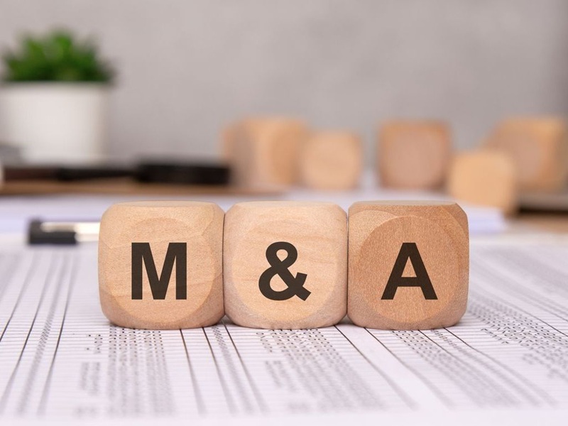 Three wooden cubes on financial spreadsheets, representing business M&A.
