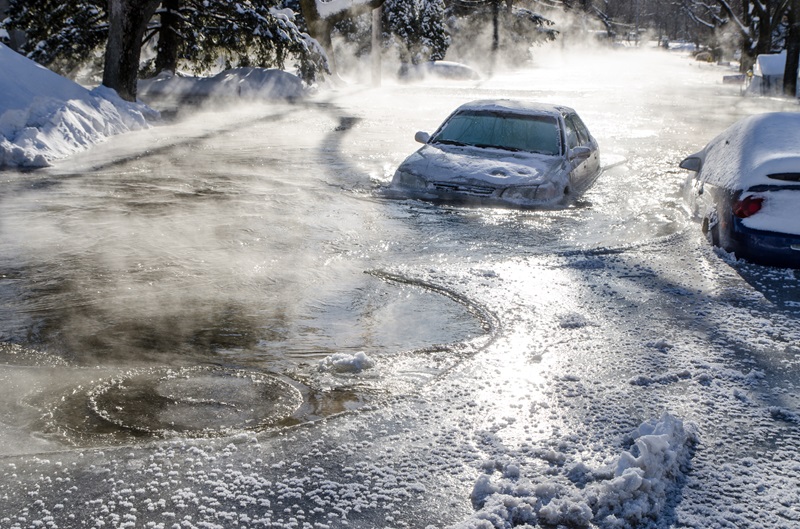 Car stuck in ice and water after the overflow of a river flood besides