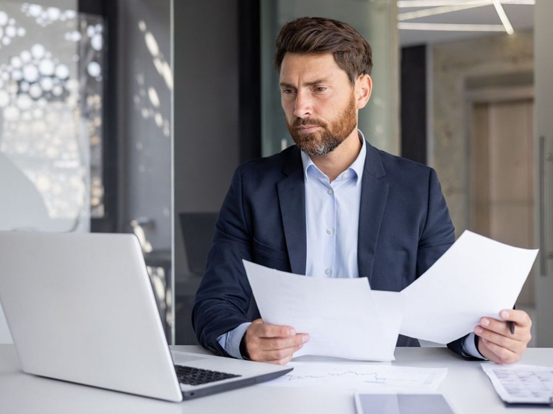 A serious young man comparing data and documents.