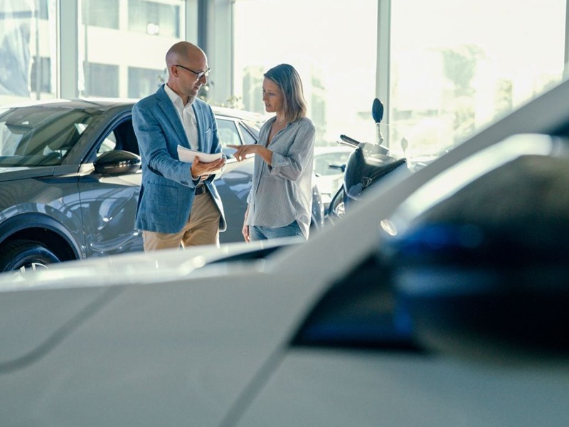Customer and car salesperson at a modern showroom