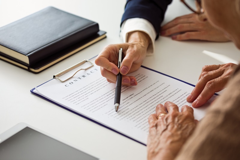 Female lawyer explaining contract with senior woman. Close up of hands, unrecognizable people.